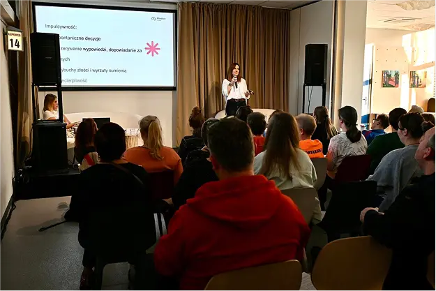 Wykład fundacji: prelegentka przed ekranem i pełna sala słuchaczy